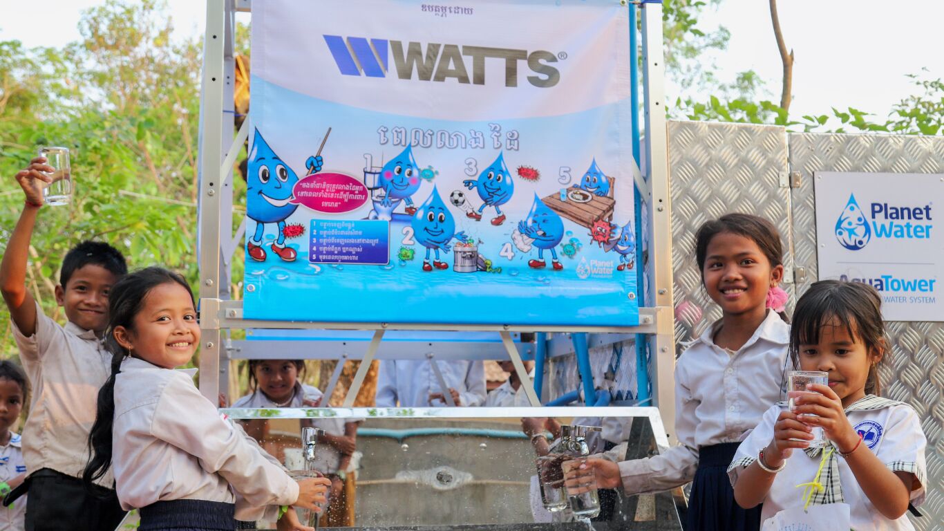 Kid gathered around a banner for World Water Day.